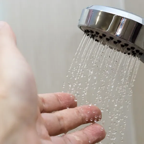Closeup of showerhead spraying water on hand